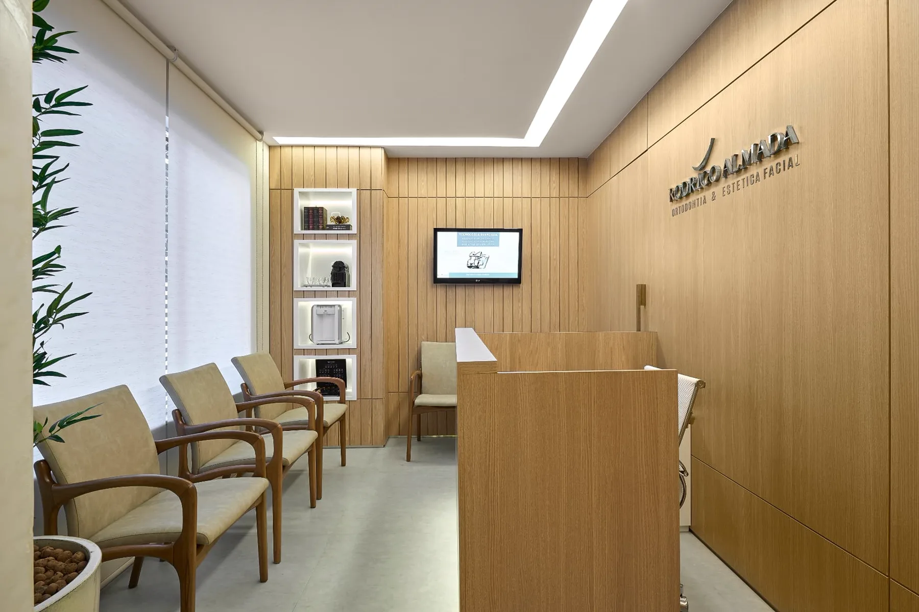 Sala de espera da unidade Lourdes, com poltronas de madeira e painéis de madeira clara