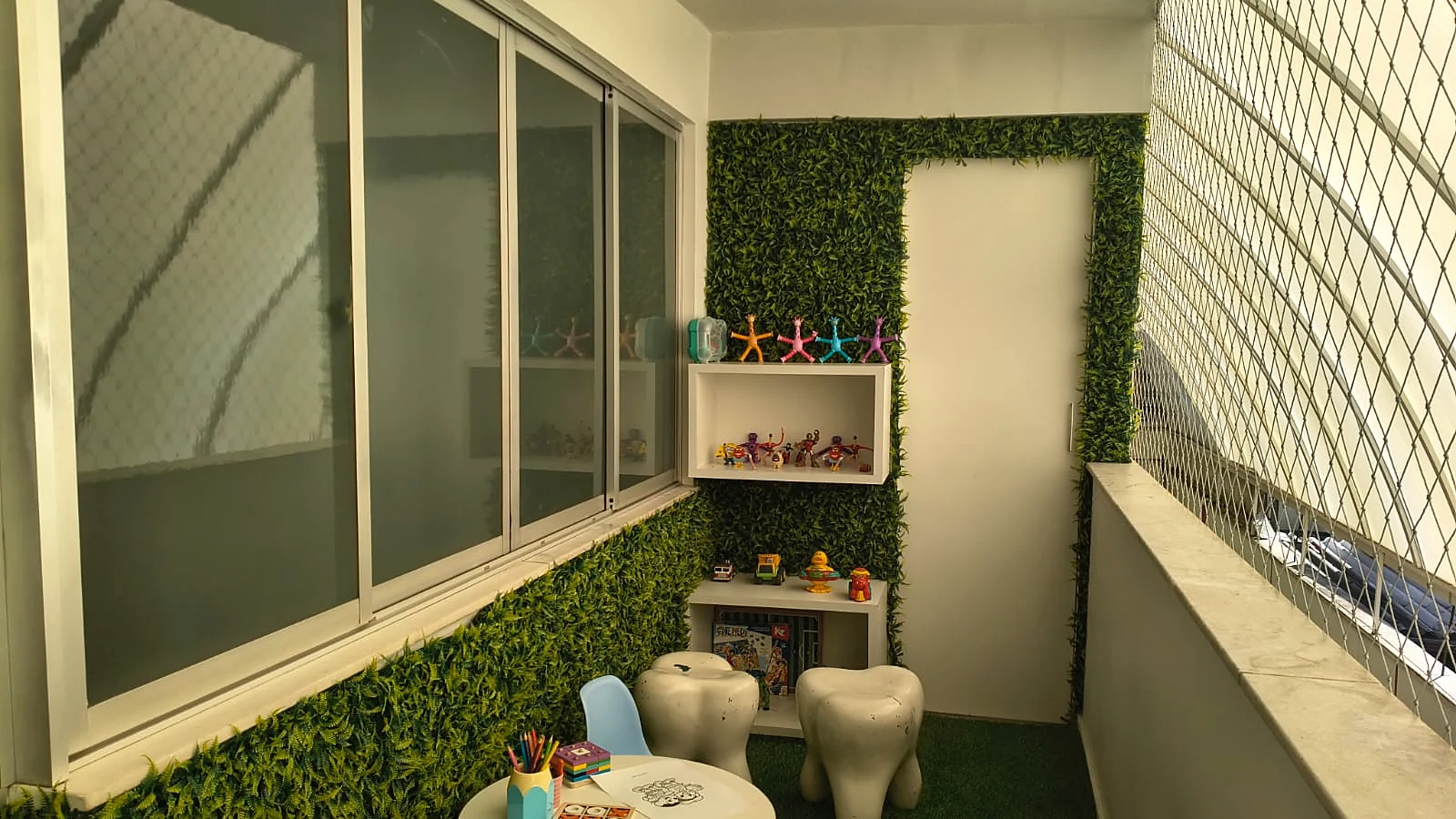 Espaço de espera infantil da unidade Floresta, com prateleiras de brinquedos, banquinhos em formato de dente e mesinha de desenho